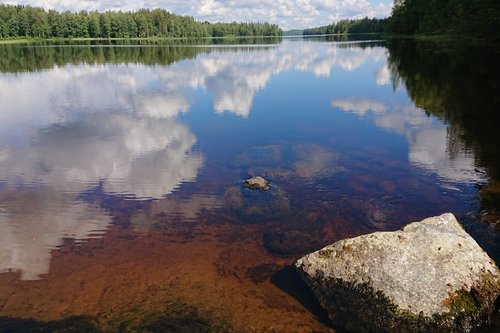 Kesäinen tyyni järven pinta, josta pilvet heijastuvat